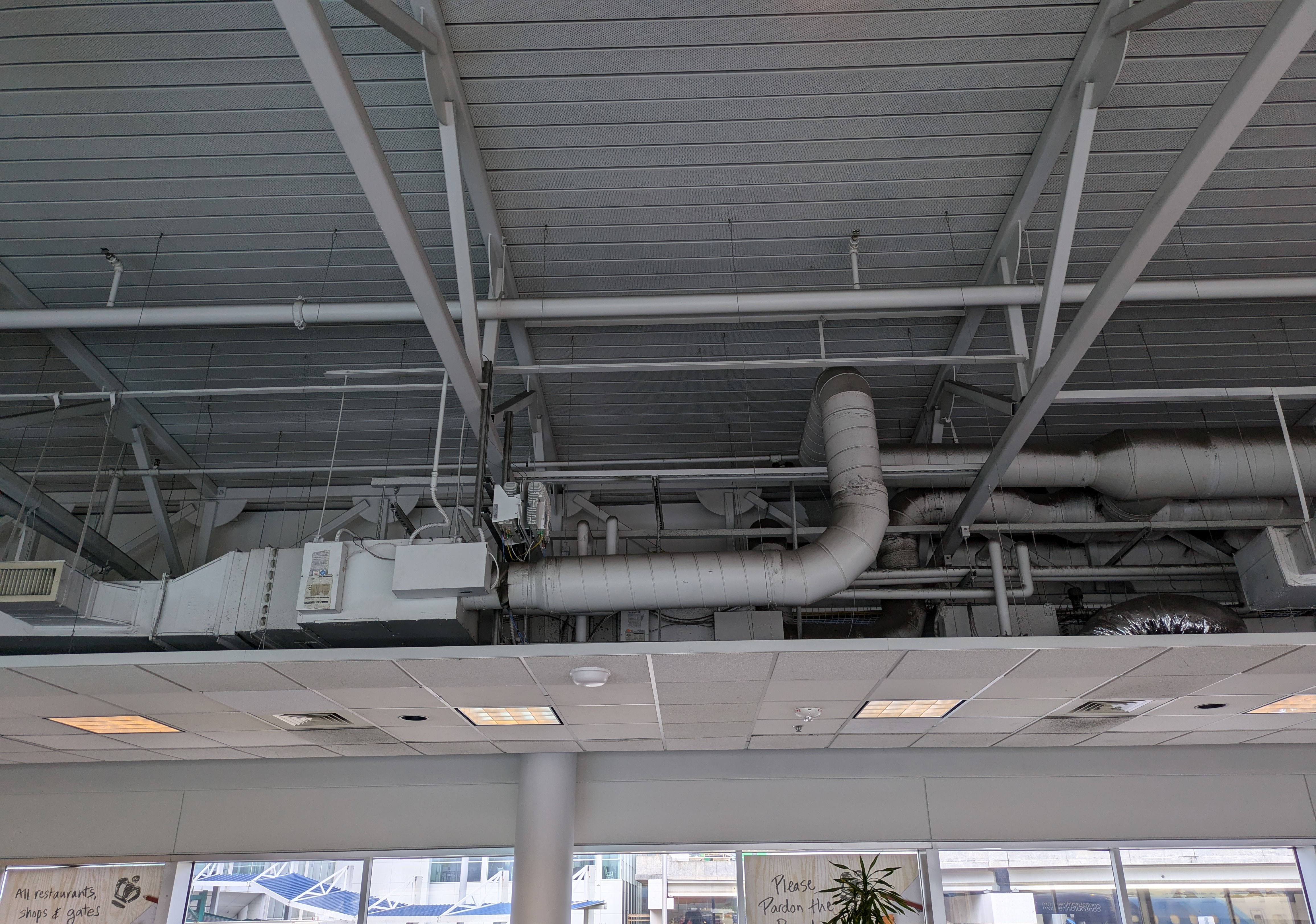 Exposed ventilation, piping, lighting, and cabling at the CLT airport looking out onto the street leading away from the airport.